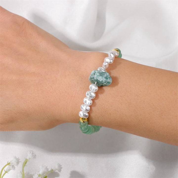 Perlenarmband mit grünen Edelsteinen und goldenen Akzenten auf Handgelenk, eleganter Schmuck.