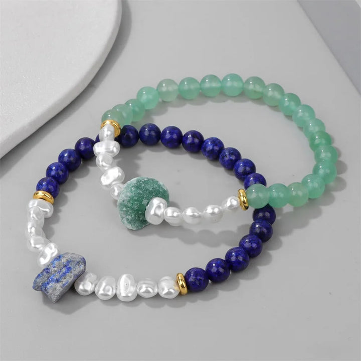 Zwei Armbänder mit grünen und blauen Perlen, verziert mit goldenen Akzenten und weißen Perlen.