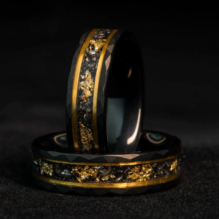 Zwei schwarze Ringe mit goldenen Akzenten und Textur, aus Karbonfaser, auf schwarzem Hintergrund.