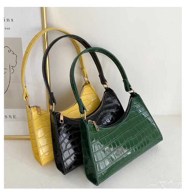 Drei Krokodilleder-Handtaschen in Gelb, Schwarz und Grün auf weißem Hintergrund.