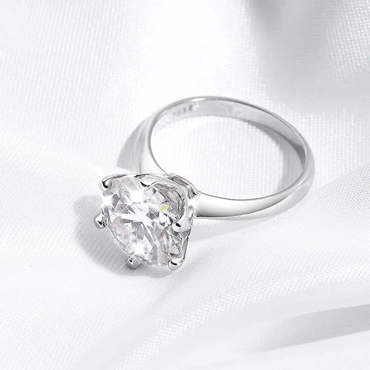 Silberner Verlobungsring mit großem, rundem Diamant auf weißem Stoffhintergrund.
