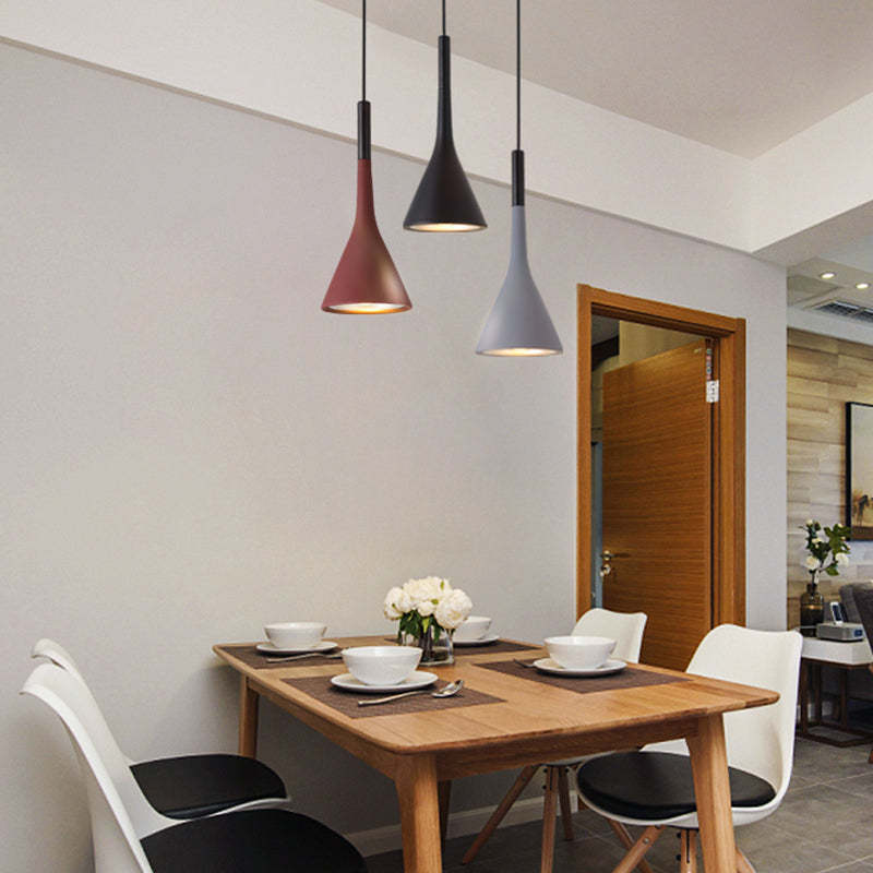 Drei moderne Pendelleuchten über Esstisch, schwarz, rot, grau, skandinavisches Design.
