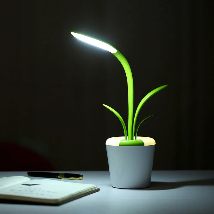 Grüne LED-Schreibtischlampe in Pflanzenform, energiesparend, modernes Design, weißer Sockel.