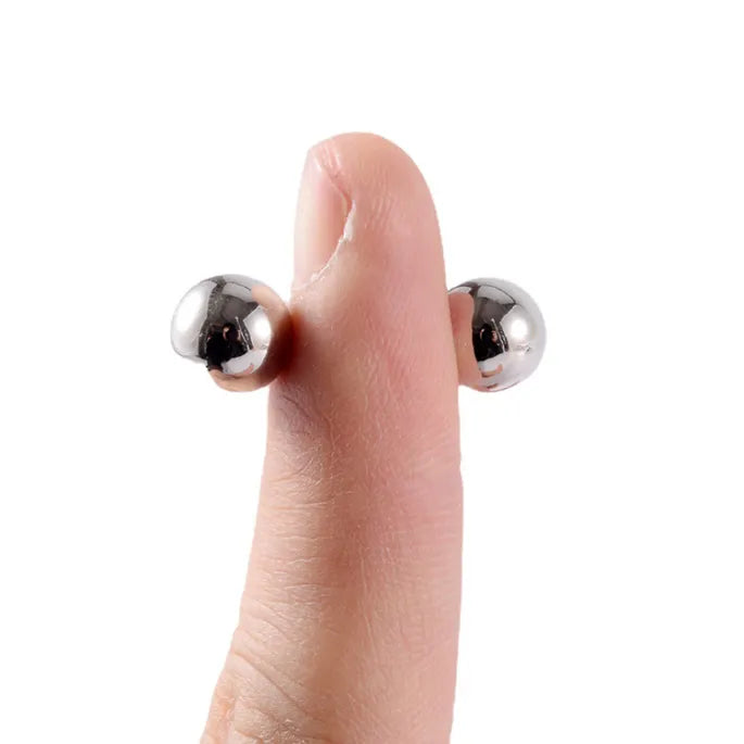 Dvě stříbrné kuličky drží magneticky na protilehlých stranách prstu a ukazují jejich velikost v porovnání s prstem. 7