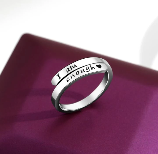 Silberner Ring mit Gravur "I am enough", Herzsymbol, auf lila Hintergrund.
