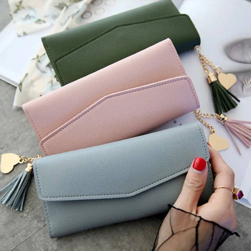 Drei Damen-Geldbörsen aus Leder in Grün, Rosa und Blau mit Quasten und Herzanhänger.
