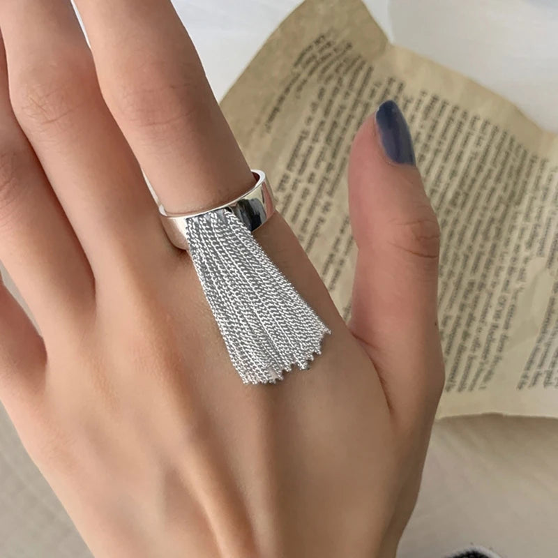 Silberner Ring mit Quasten-Design auf Hand, eleganter Schmuck, modisches Accessoire.