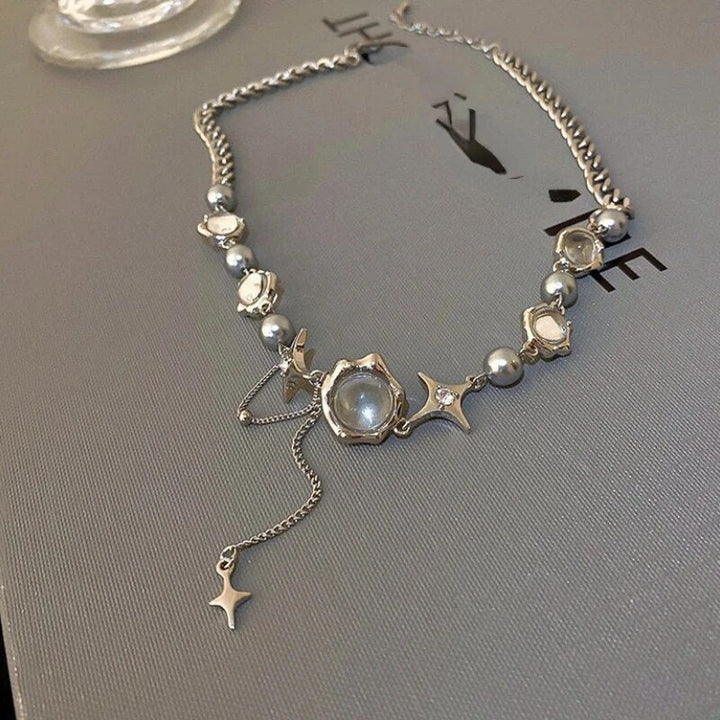 Silberne Halskette mit Perlen und Sternanhängern auf grauem Hintergrund, eleganter Schmuck.