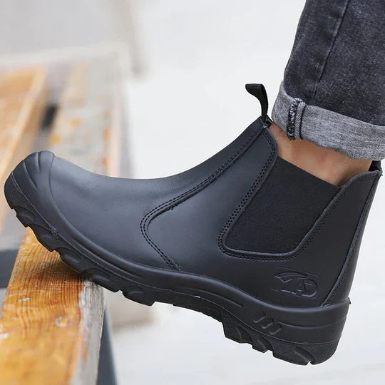 Černá kotníková bota s elastickým bokem a vyztuženou špicí, nasazená na noze, zblízka na schodu 1