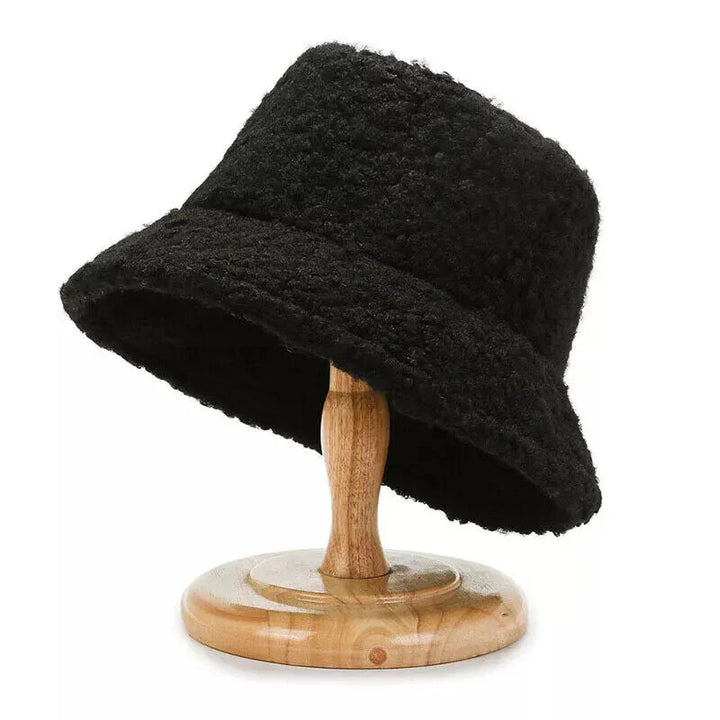 Schwarzer Damen-Bucket-Hut aus Wolle auf Holzständer, modisch und warm.
