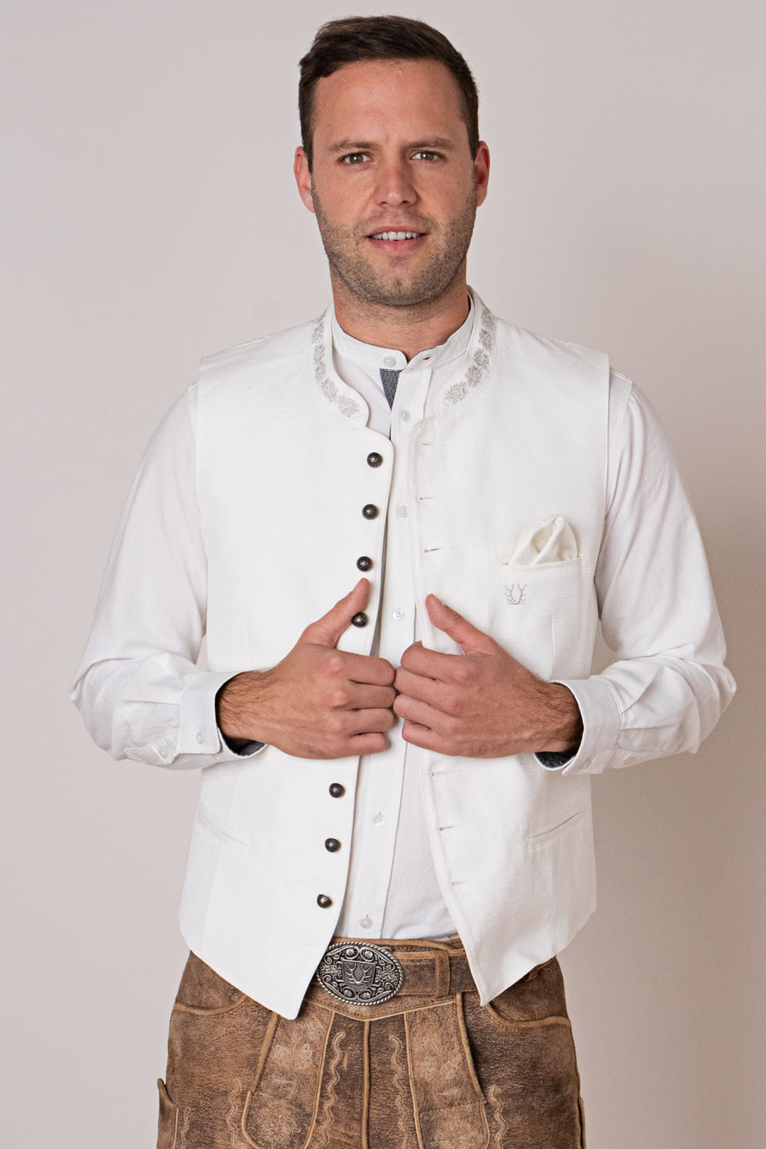 Mann in weißer Trachtenweste und Lederhose, traditionelles bayerisches Outfit, festliche Kleidung.