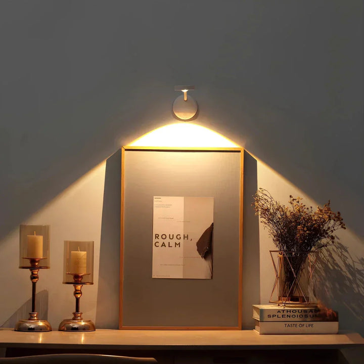 Wandleuchte über gerahmtem Bild, moderne Dekoration, warmes Licht, minimalistisch, Wohnzimmer.