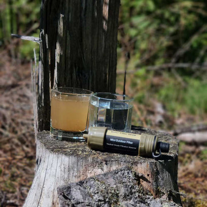 Mini Outdoor Wasserfilter auf Baumstumpf, zwei Gläser Wasser, Natur, tragbar, Campingzubehör.