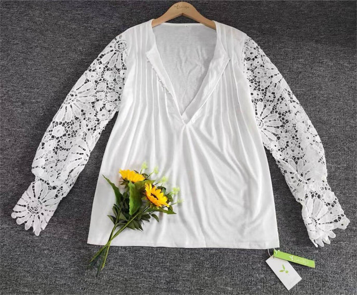 Weiße Bluse mit Spitzenärmeln und V-Ausschnitt, auf grauem Hintergrund, mit Sonnenblumenstrauß.