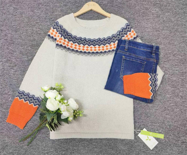 Grauer Strickpullover mit orange-blauem Muster, blaue Jeans, weiße Blumen, auf grauem Hintergrund.