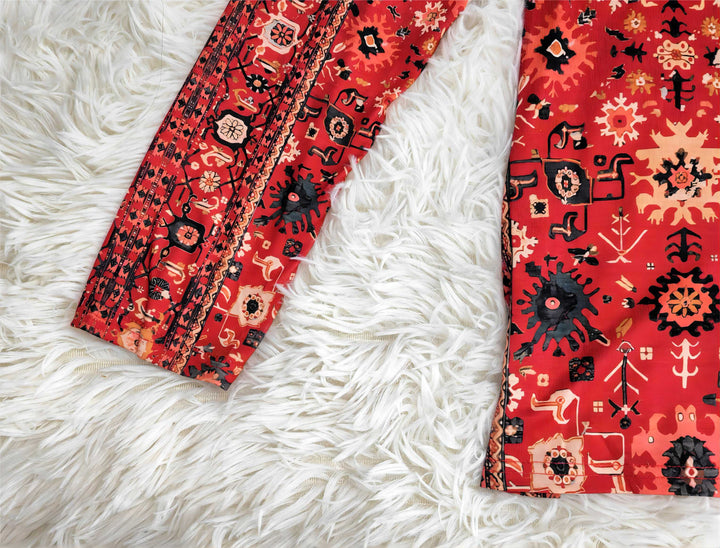 Rotes Ethno-Kleid mit schwarzen Mustern auf weißem Kunstfell-Teppich.