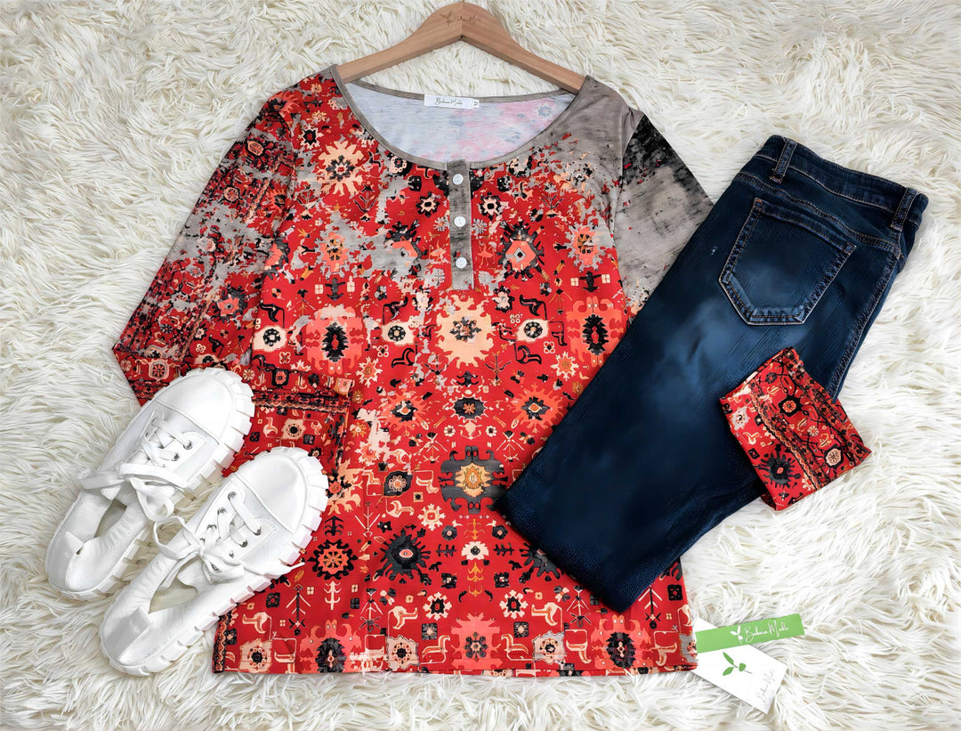 Bunte Damenbluse mit orientalischem Muster, blaue Jeans, weiße Sneaker auf weißem Teppich.