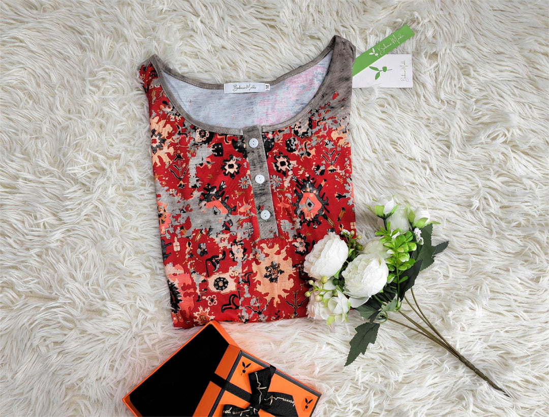 Rotes Damenkleid mit Blumenmuster auf weißem Teppich, Geschenkbox und Blumenstrauß.