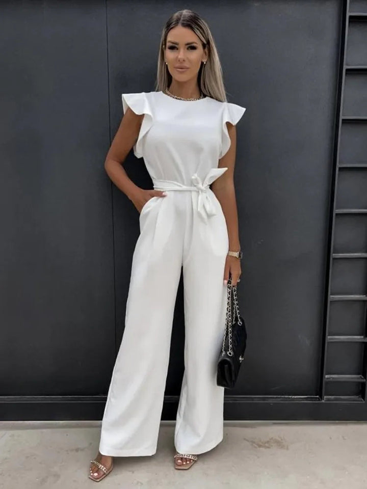 Frau in weißem Jumpsuit mit Schmetterlingsärmeln, elegantes Sommeroutfit, Vintage-Streetwear.