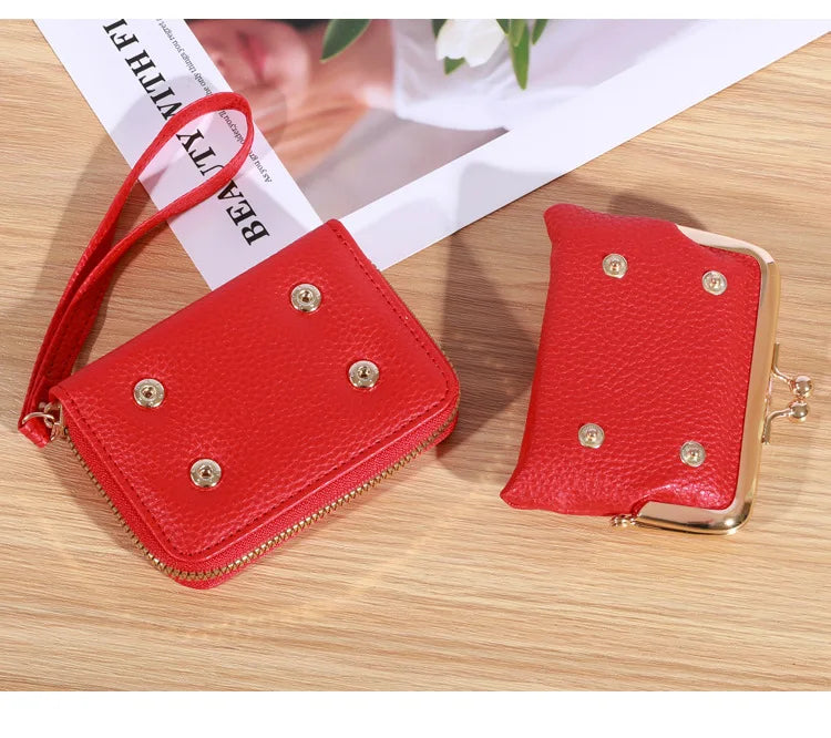 Rote Lederhandtasche und Geldbörse mit goldenen Nieten auf Holztisch.