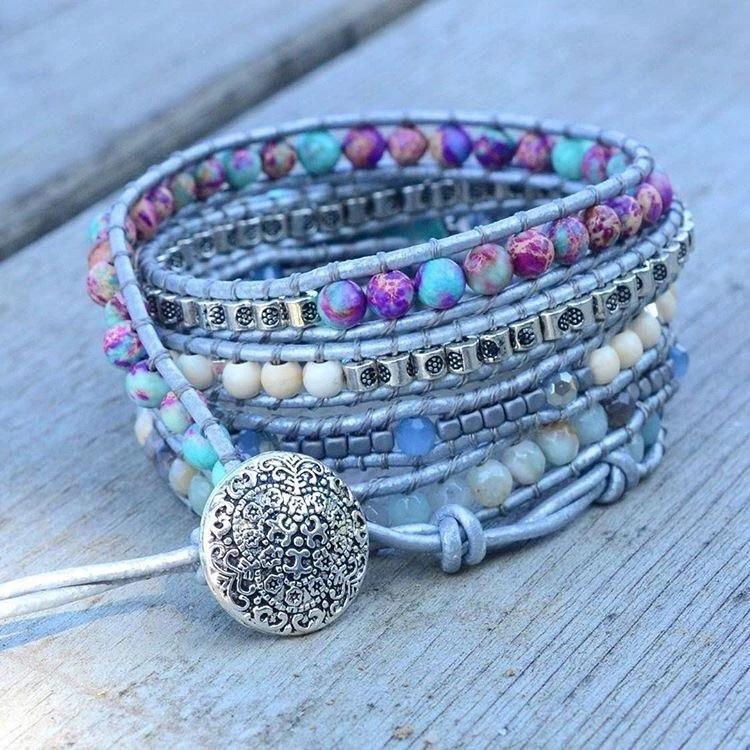 Mehrfarbiges Wickelarmband mit Edelsteinen und silbernem Verschluss auf Holzoberfläche.