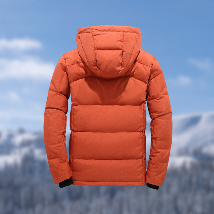 Orangefarbene Daunenjacke mit Kapuze, Winterbekleidung, isoliert, vor verschneiter Berglandschaft.