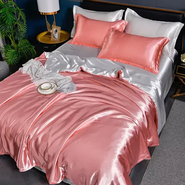 Luxuriöses rosa und silbernes Seidensatin-Bettwäsche-Set mit Kissen und Decke im Schlafzimmer.