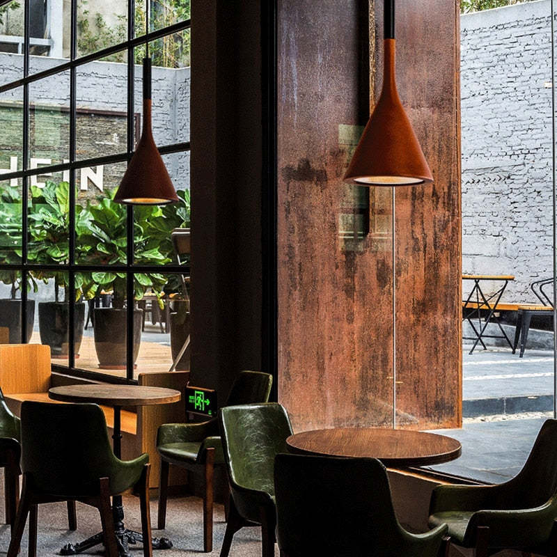 Moderne Café-Inneneinrichtung mit grünen Stühlen, Holztischen und großen Fenstern.