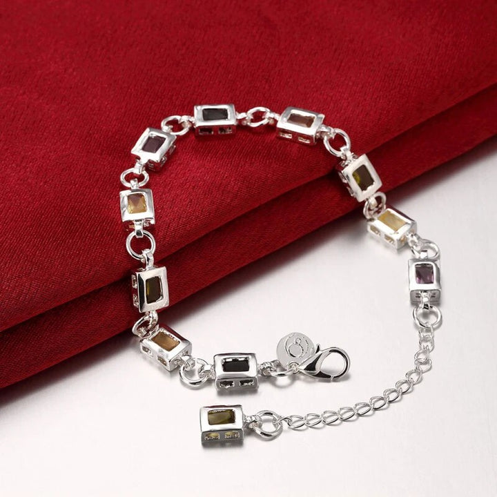 Silberarmband mit rechteckigen Edelsteinen auf rotem Stoff, elegantes Schmuckdesign.