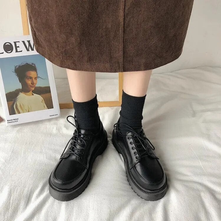 Schwarze Damen-Schnürschuhe aus Leder, modisch, robust, mit dicker Sohle, auf weißem Hintergrund.