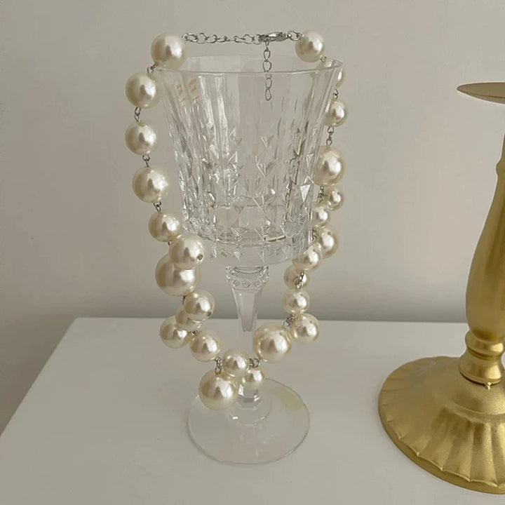Perlenkette auf Kristallglas, elegante Schmuckpräsentation, luxuriöses Accessoire, Dekoration.
