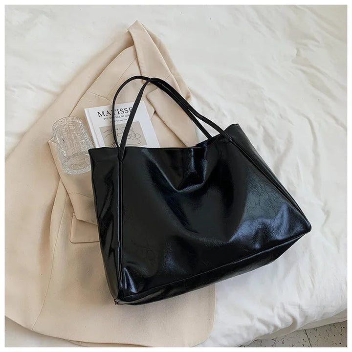 Schwarze Ledertasche auf beigem Mantel, stilvoll, elegant, Damenmode, Accessoire.