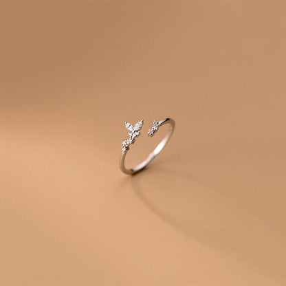 Silberner offener Ring mit Schmetterlingsdesign und Zirkonia-Steinen auf beigem Hintergrund.