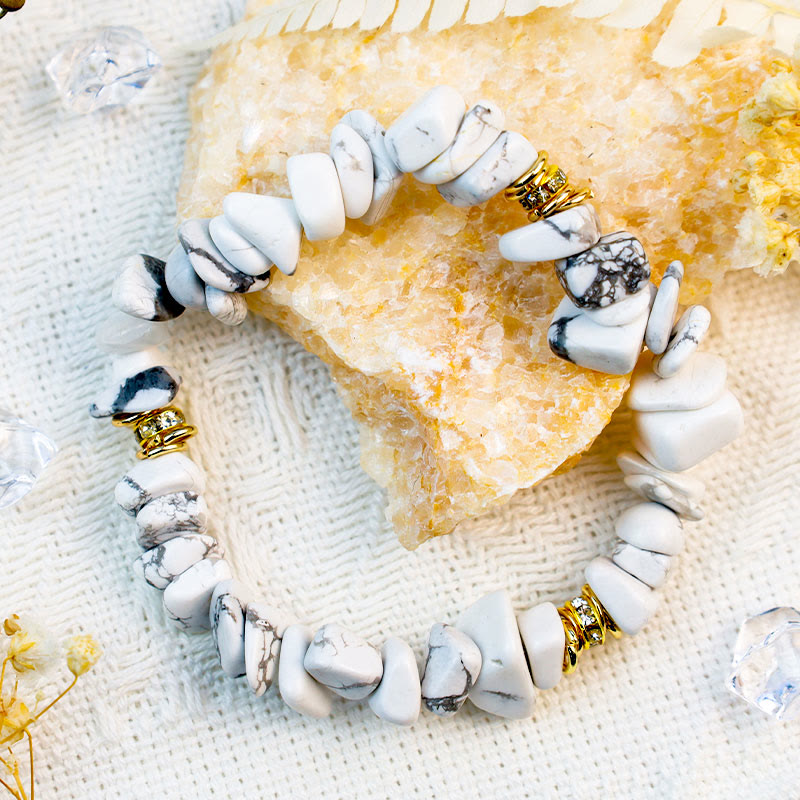Weiße Howlith-Armband mit goldenen Akzenten auf hellem Hintergrund, Schmuck, Modeaccessoire.
