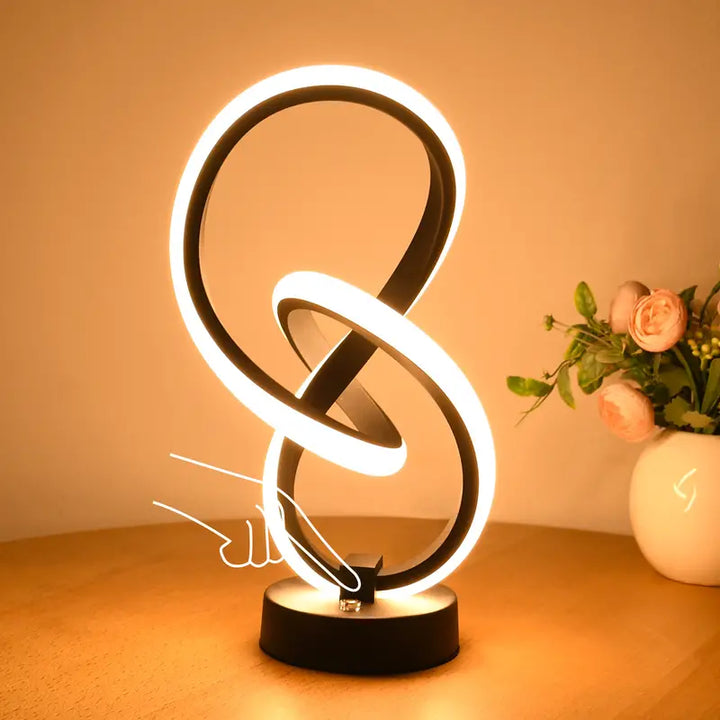 Moderne LED-Tischlampe, schwarz, geschwungenes Design, warmweißes Licht, dekorativ.