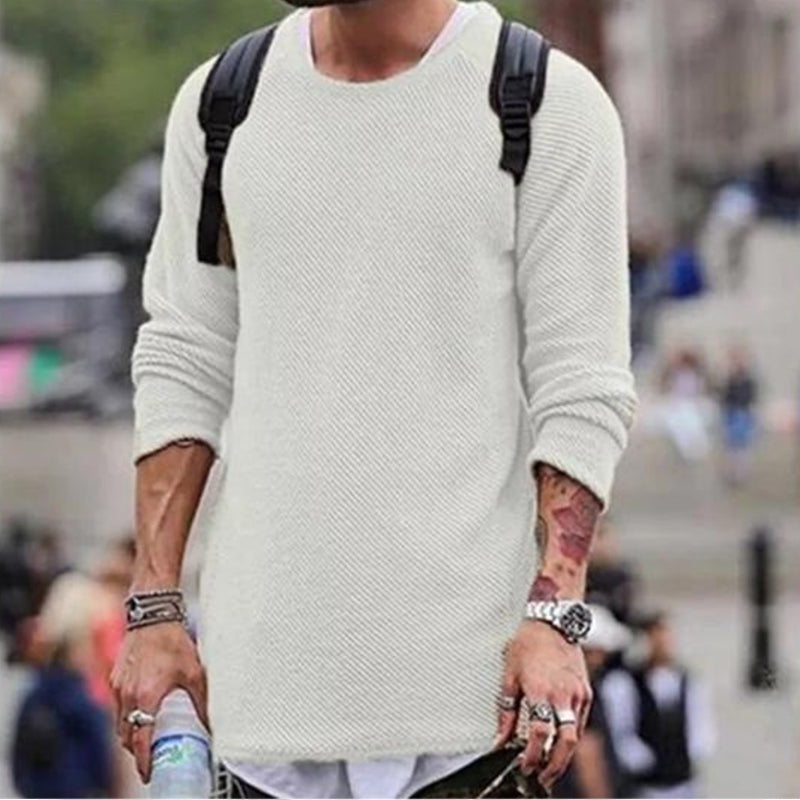 Mann in weißem Strickpullover mit Rucksack, urbaner Hintergrund, modischer Freizeitlook.