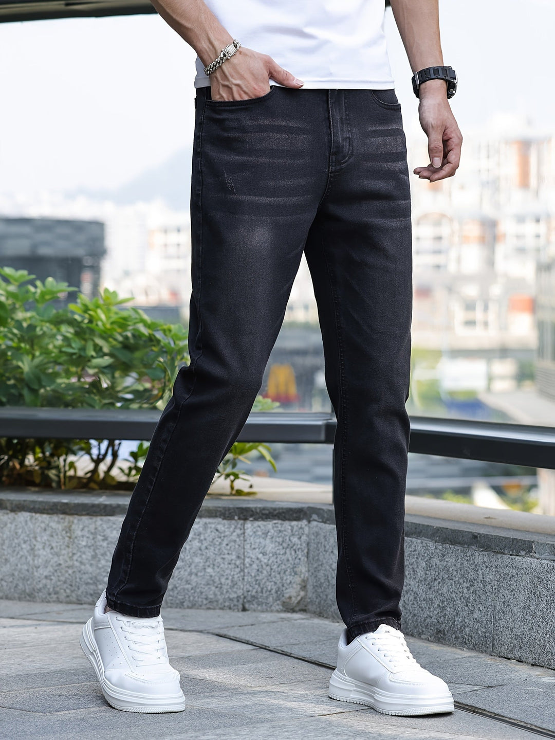 Mann in schwarzer Jeans und weißen Sneakers, urbaner Hintergrund, lässige Mode.