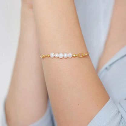 Goldenes Armband mit weißen Perlen, eleganter Schmuck, Damenaccessoire, Nahaufnahme.
