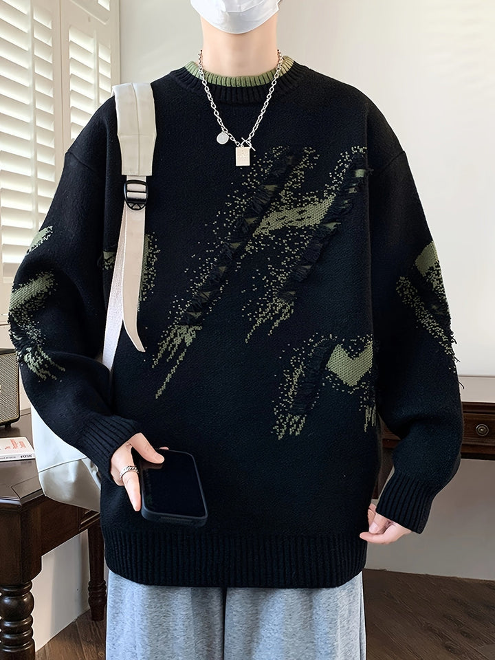 Mann in schwarzem Strickpullover mit grünem Muster, hält Smartphone, trägt weiße Maske.