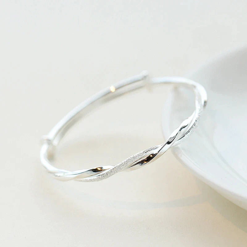 Silberner Armreif, gedrehtes Design, eleganter Schmuck, Damenaccessoire, Geschenkidee.