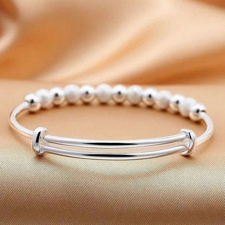 Silberarmband mit Perlen auf beigem Hintergrund, elegantes Schmuckdesign, Damenaccessoire.
