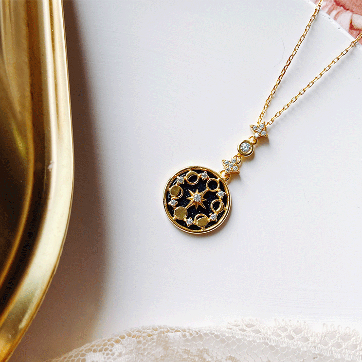 Goldene Halskette mit Mond- und Sternanhänger, schwarzer Hintergrund, elegantes Schmuckdesign.