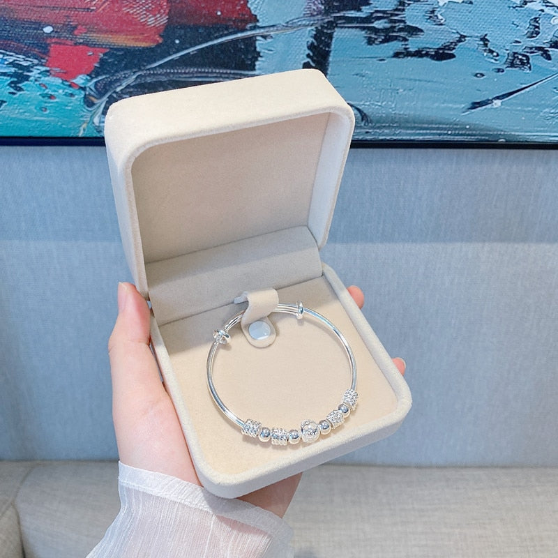 Silberarmband mit Perlen in beiger Schmuckschatulle, elegantes Design, Geschenkidee.
