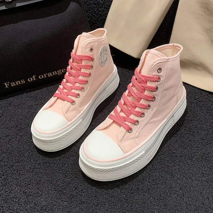 Rosa High-Top-Sneaker mit dicker Sohle und pinken Schnürsenkeln auf schwarzem Teppich.