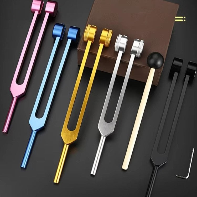 Bunte Stimmgabeln aus Metall, Set mit fünf Farben, auf schwarzem Hintergrund.