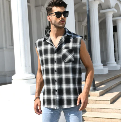 Mann in ärmellosem schwarz-weiß kariertem Hemd, Sonnenbrille, Jeans, vor Säulen.