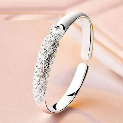 Silberner Pfauenarmreif, elegantes Design, Schmuck für Damen, luxuriöses Accessoire.