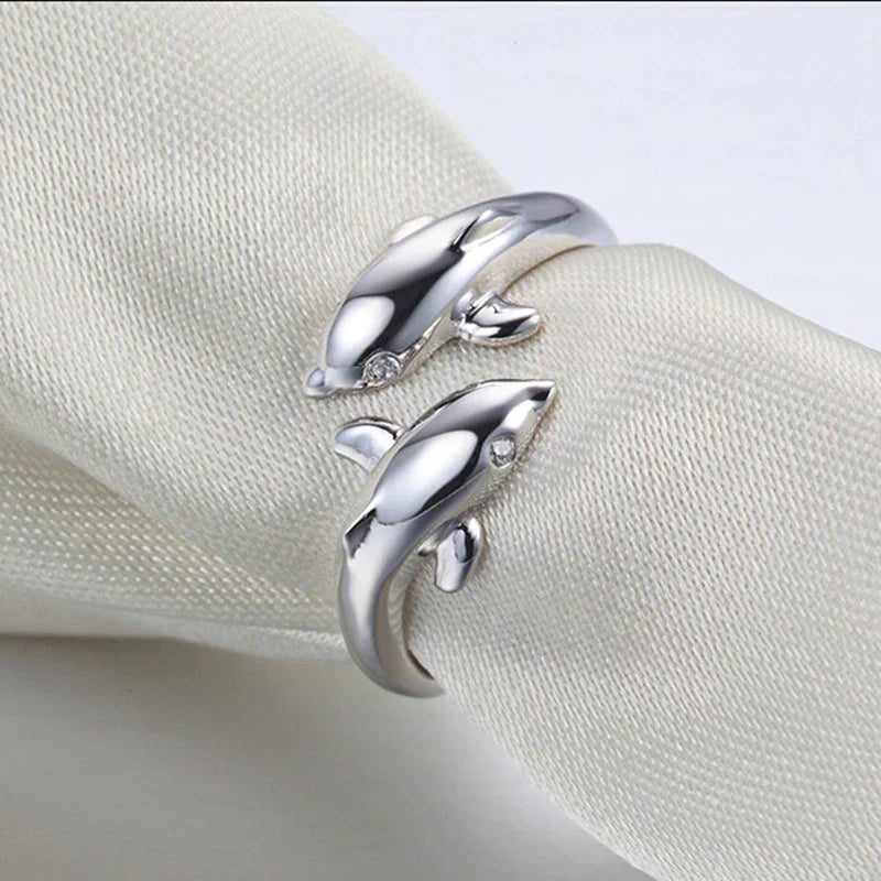 Silberne Delfin-Ringe auf weißem Stoff, eleganter Schmuck, Geschenkidee, modisch.