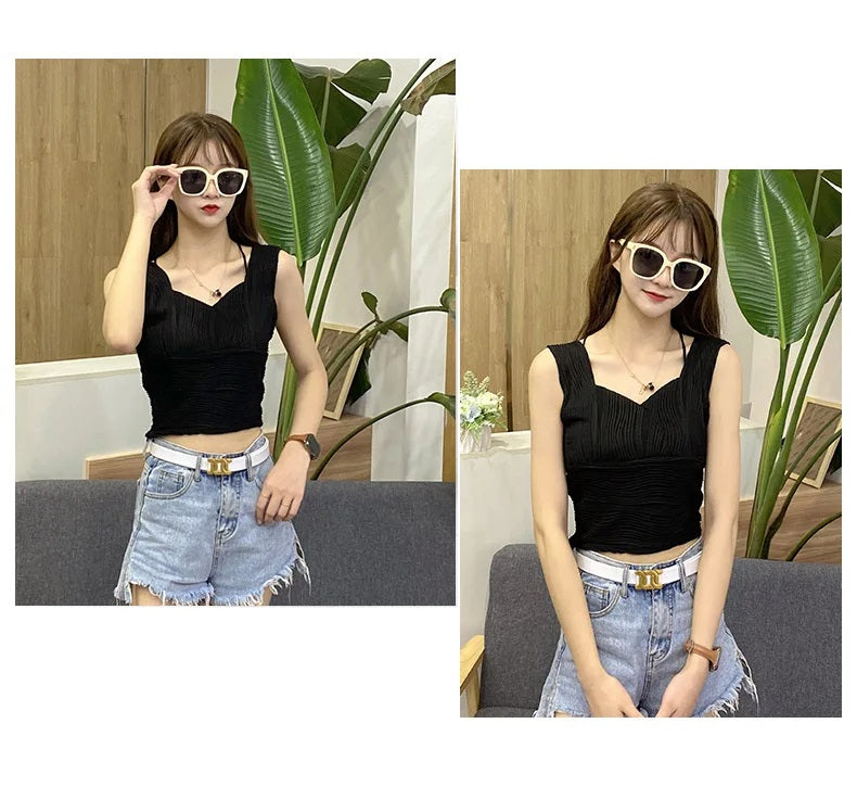 Frau in schwarzem Top und Jeansshorts, trägt Sonnenbrille, sitzt auf Sofa, moderne Mode.