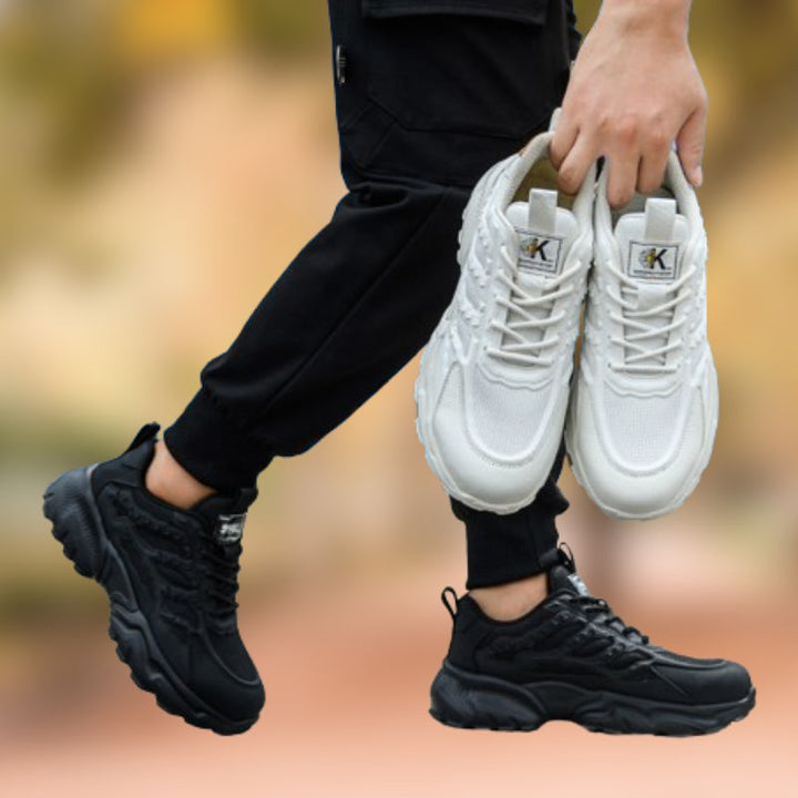 Person hält weiße Sneaker, trägt schwarze Sneaker, sportlich, modisch, Unisex-Schuhe.